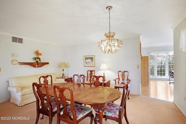 dining area with baseboards, visible vents, ornamental molding, light colored carpet, and a chandelier