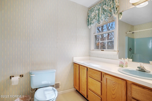 bathroom with vanity, toilet, and wallpapered walls