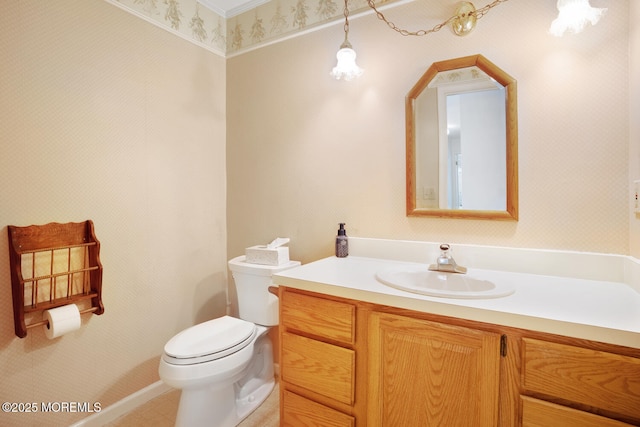 bathroom featuring toilet, wallpapered walls, and vanity