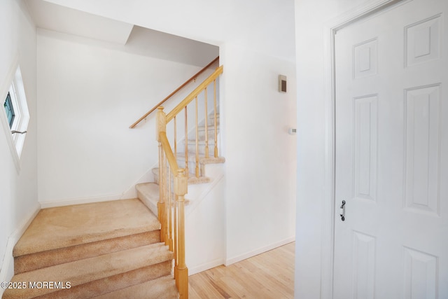 staircase featuring wood finished floors and baseboards