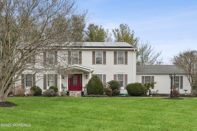 colonial home with solar panels and a front yard