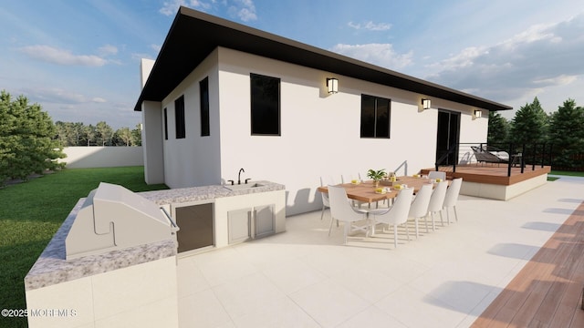 rear view of property with a wooden deck, stucco siding, outdoor dining area, area for grilling, and a sink