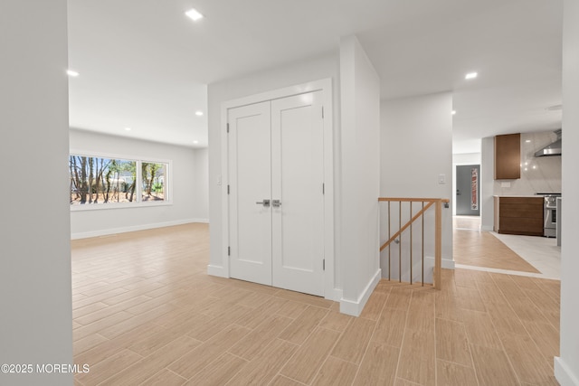 hallway with recessed lighting, an upstairs landing, baseboards, and light wood finished floors