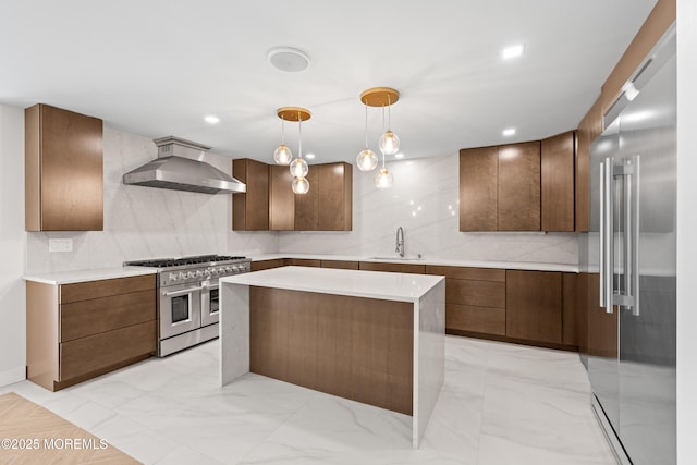 kitchen with high end appliances, a sink, light countertops, wall chimney exhaust hood, and backsplash