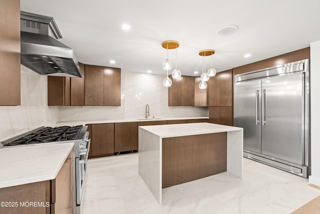 kitchen with high quality appliances, marble finish floor, a sink, tasteful backsplash, and wall chimney range hood