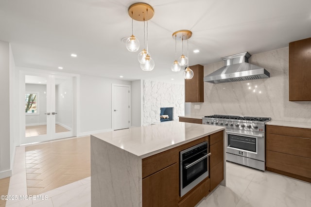 kitchen featuring tasteful backsplash, a center island, recessed lighting, stainless steel appliances, and wall chimney exhaust hood