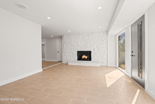 unfurnished living room featuring recessed lighting, a fireplace, baseboards, and wood tiled floor