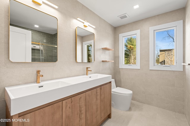 full bathroom featuring a sink, toilet, tile walls, and a stall shower