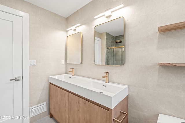 full bathroom featuring a tile shower, visible vents, tile walls, and a sink