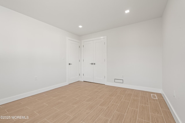 spare room featuring recessed lighting, visible vents, baseboards, and wood finish floors