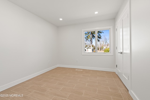 spare room with wood finish floors, baseboards, and recessed lighting