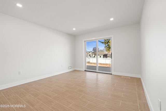 spare room featuring recessed lighting, light wood-style floors, and baseboards