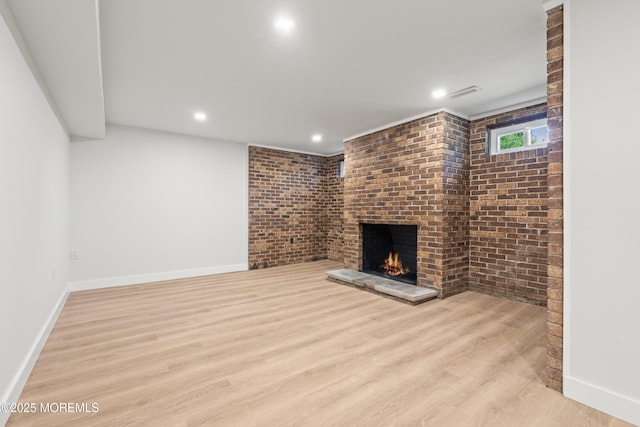 unfurnished living room with a brick fireplace, wood finished floors, visible vents, and baseboards