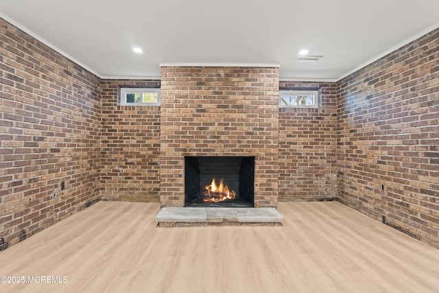 unfurnished living room with visible vents, a healthy amount of sunlight, a brick fireplace, and wood finished floors