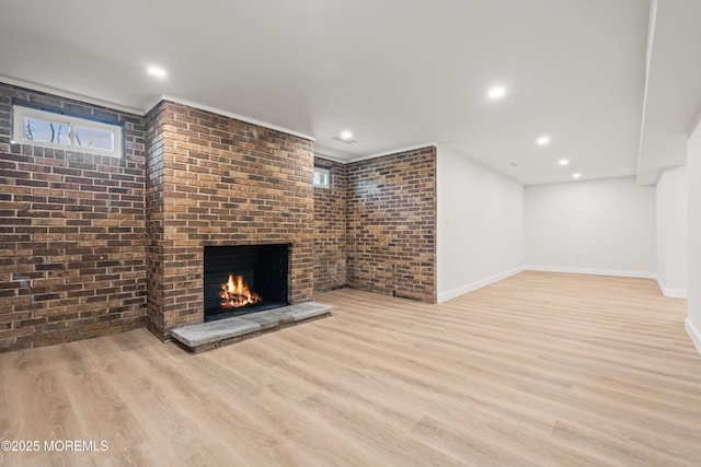 unfurnished living room with a brick fireplace, brick wall, baseboards, recessed lighting, and wood finished floors