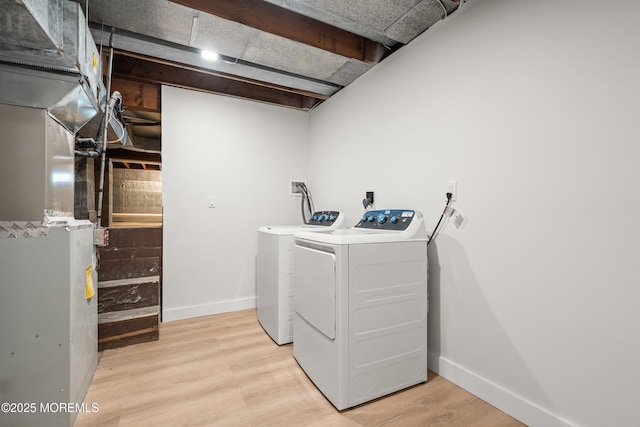 washroom with washer and dryer, baseboards, laundry area, and light wood finished floors