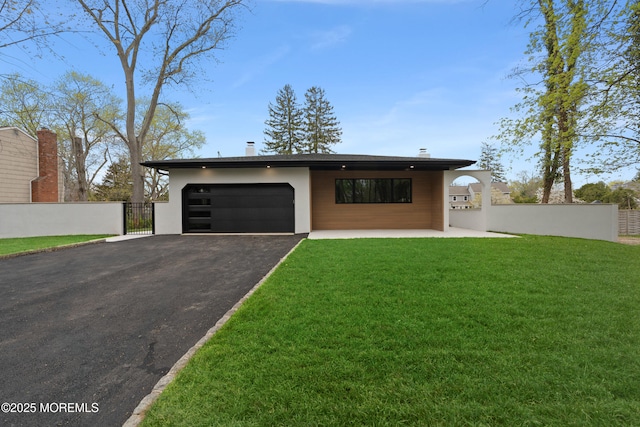 contemporary home with a front lawn, driveway, fence, a garage, and stucco siding
