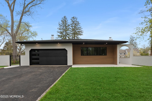 contemporary home featuring a chimney, a front lawn, aphalt driveway, and a garage
