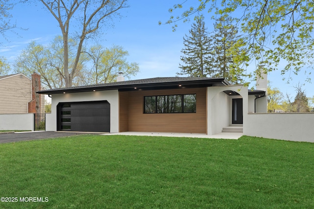 view of front of property featuring stucco siding, aphalt driveway, a garage, and a front yard