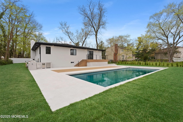 back of house with stucco siding, an outdoor pool, a patio, and a lawn
