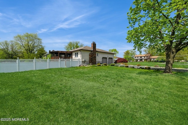 view of yard with an attached garage and fence