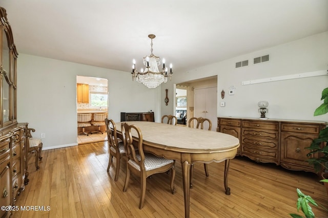 dining area with an inviting chandelier, light wood-type flooring, and visible vents