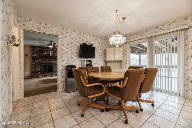 dining area featuring light tile patterned floors, an inviting chandelier, a fireplace, and wallpapered walls