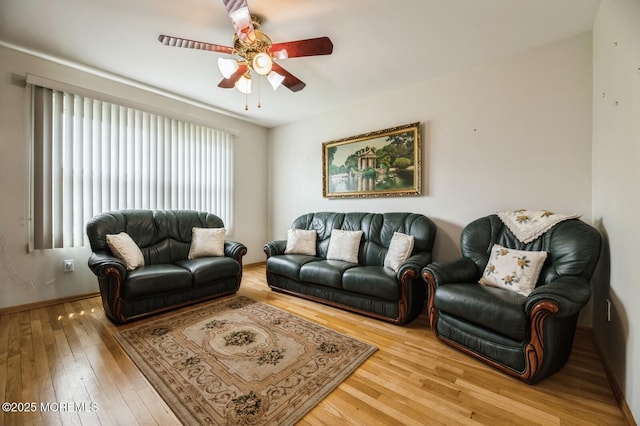 living room with light wood-style floors, a ceiling fan, and baseboards