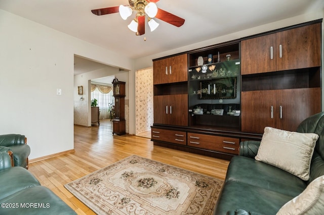 living room with a ceiling fan, baseboards, and light wood finished floors