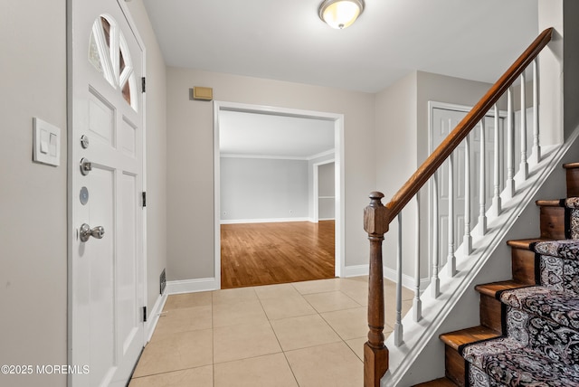 foyer entrance featuring light tile patterned floors, stairs, and baseboards