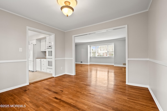 interior space with light wood finished floors, baseboards, and ornamental molding