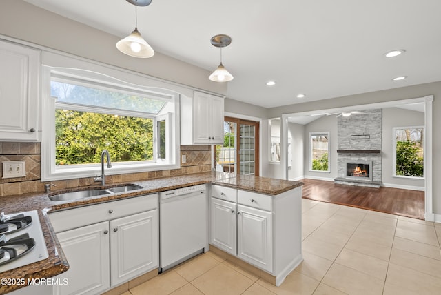 kitchen with a sink, white appliances, white cabinetry, and light tile patterned floors