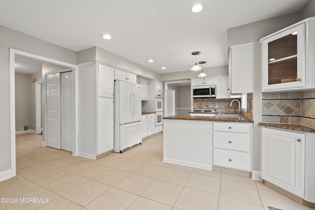 kitchen featuring white cabinets, white appliances, a peninsula, and a sink