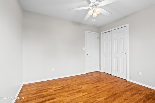 unfurnished bedroom featuring a closet, ceiling fan, baseboards, and wood finished floors