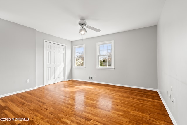 unfurnished bedroom with visible vents, a ceiling fan, a closet, light wood-style floors, and baseboards