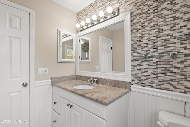 bathroom with vanity, toilet, and wainscoting