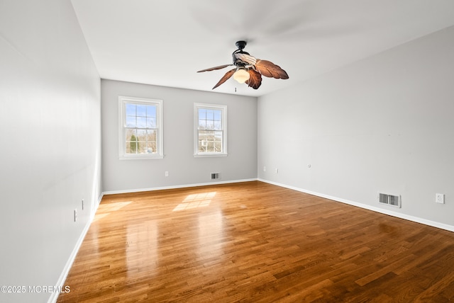 unfurnished room with baseboards, wood finished floors, visible vents, and ceiling fan