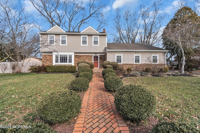 view of front of property featuring stone siding, a front lawn, and a chimney