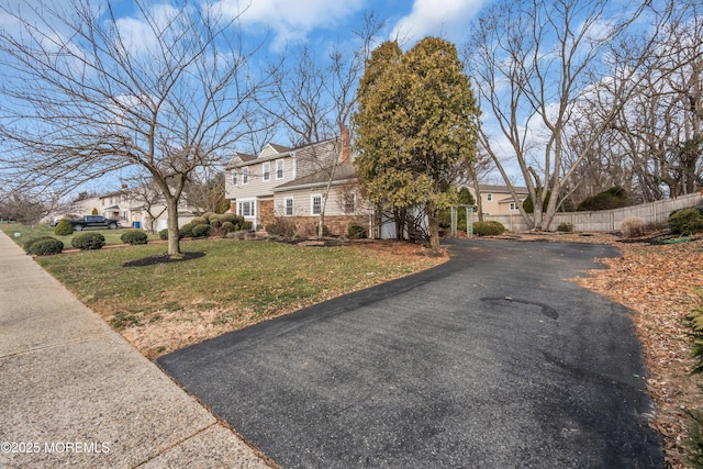 view of front of home with a front lawn, fence, and brick siding