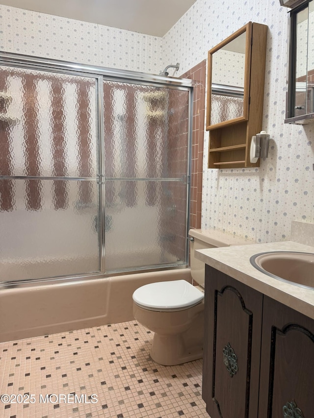 full bath featuring wallpapered walls, toilet, shower / bath combination with glass door, tile patterned floors, and vanity