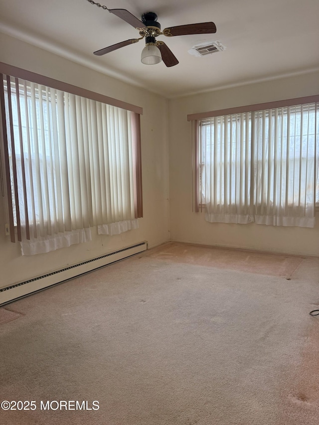 carpeted spare room featuring baseboard heating, ceiling fan, and visible vents