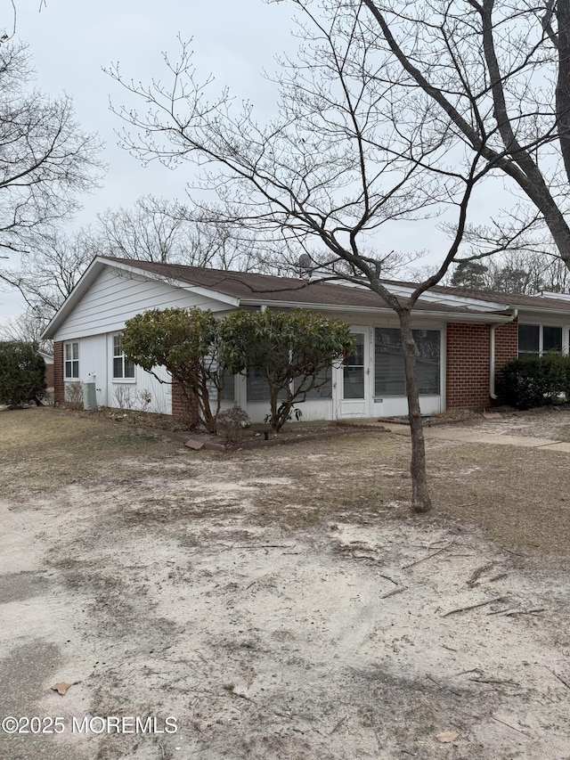 view of front facade featuring brick siding and dirt driveway