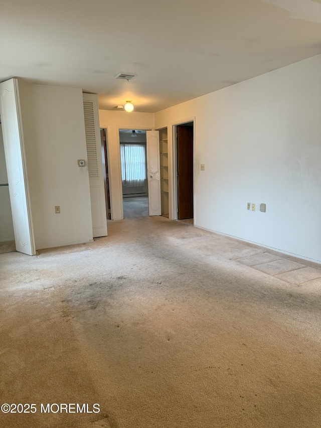 spare room featuring visible vents and light colored carpet