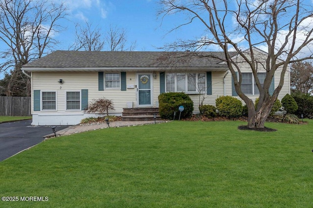 ranch-style house with fence, a front yard, and a shingled roof