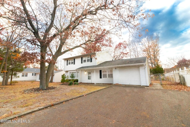 traditional-style home featuring aphalt driveway, fence, and a garage