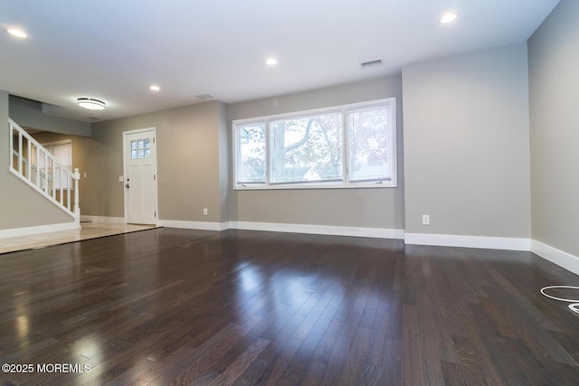 unfurnished living room featuring visible vents, stairs, baseboards, and wood finished floors