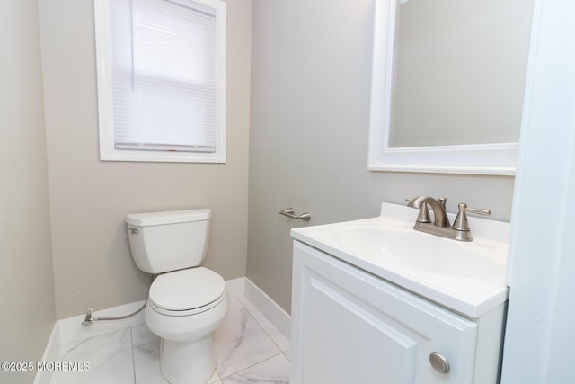 half bathroom featuring vanity, toilet, baseboards, and marble finish floor