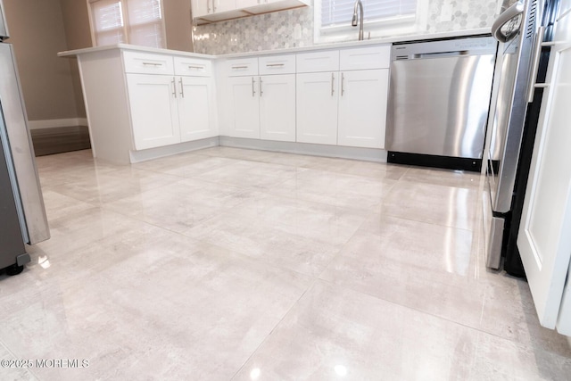 kitchen with a sink, white cabinets, fridge, and stainless steel dishwasher