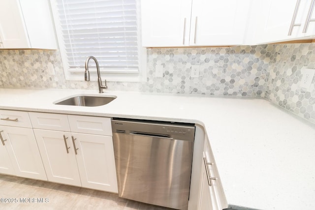 kitchen featuring tasteful backsplash, a sink, white cabinetry, and stainless steel dishwasher