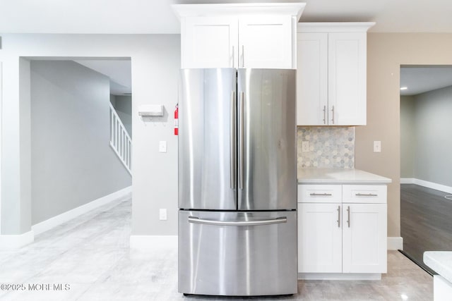 kitchen with backsplash, white cabinets, light countertops, and freestanding refrigerator